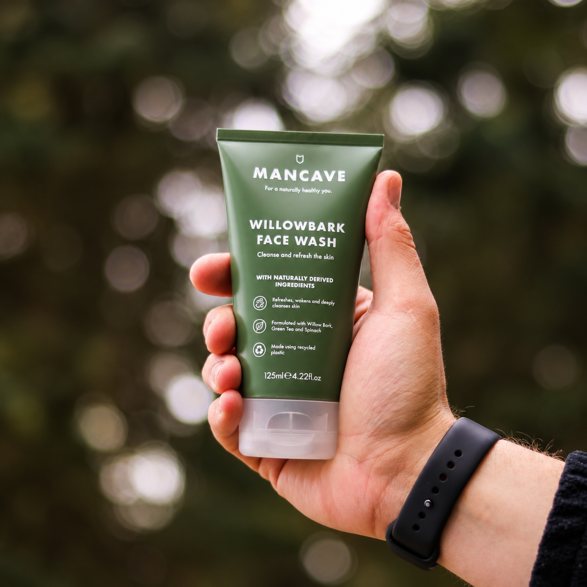 ManCave Willowbark Face Wash holdes i hånden utendørs med natur i bakgrunnen