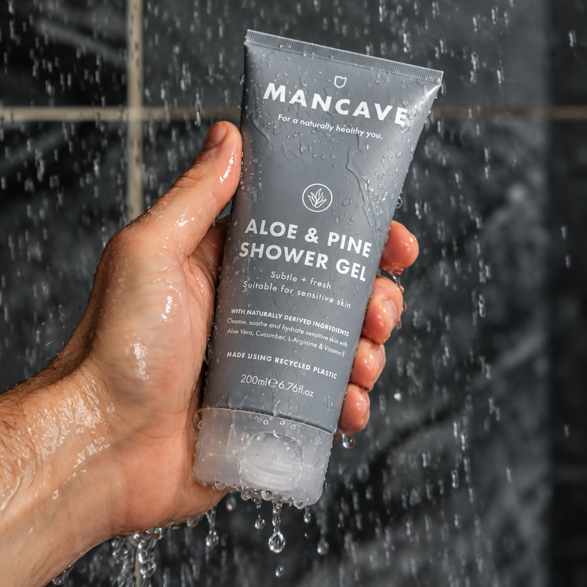 ManCave Aloe & Pine Shower Gel holdes i hånden under rennende vann i dusjen