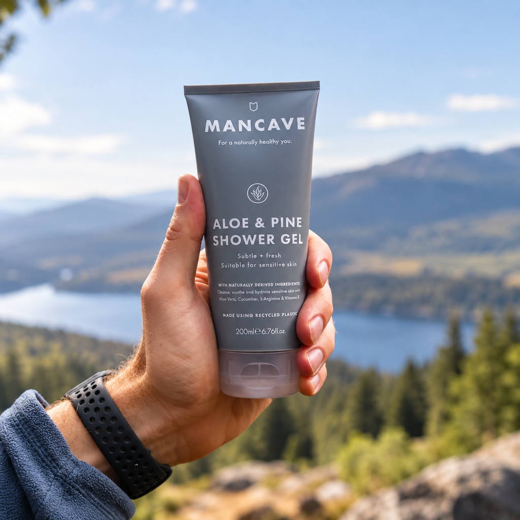 ManCave Aloe & Pine Shower Gel holdes i hånden utendørs med fjell og natur i bakgrunnen