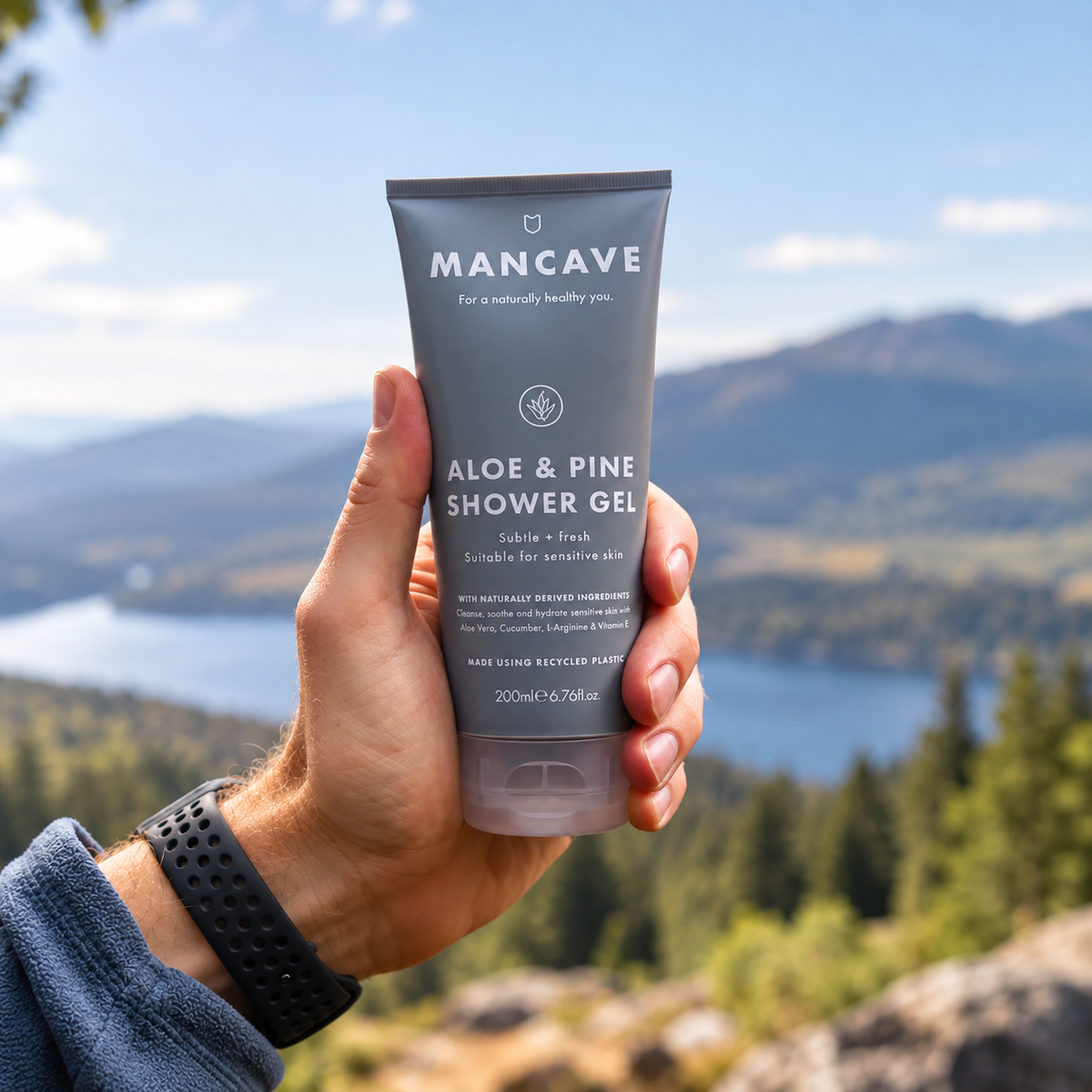 ManCave Aloe & Pine Shower Gel holdes i hånden utendørs med fjell og natur i bakgrunnen