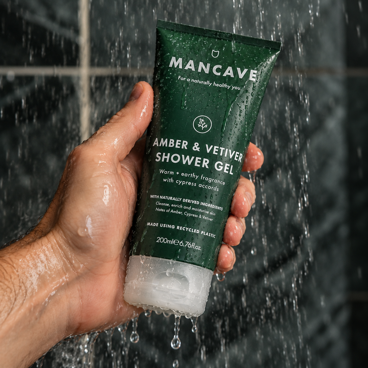 ManCave Amber & Vetiver Shower Gel holdes i hånden under rennende vann i dusjen