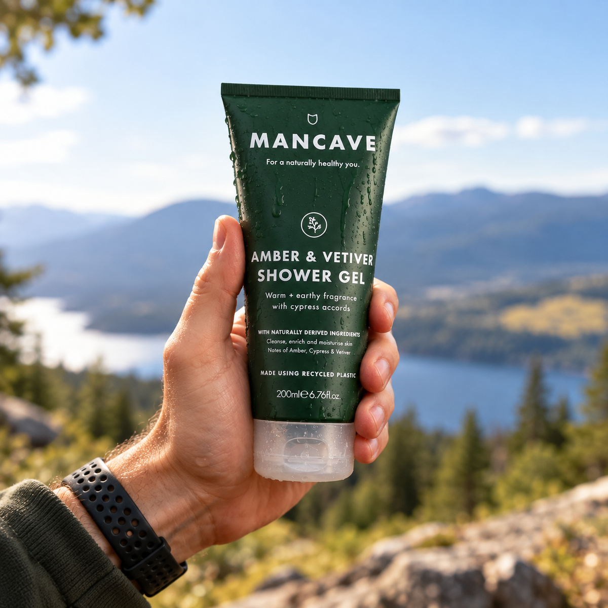 ManCave Amber & Vetiver Shower Gel holdes i hånden utendørs med fjell og natur i bakgrunnen