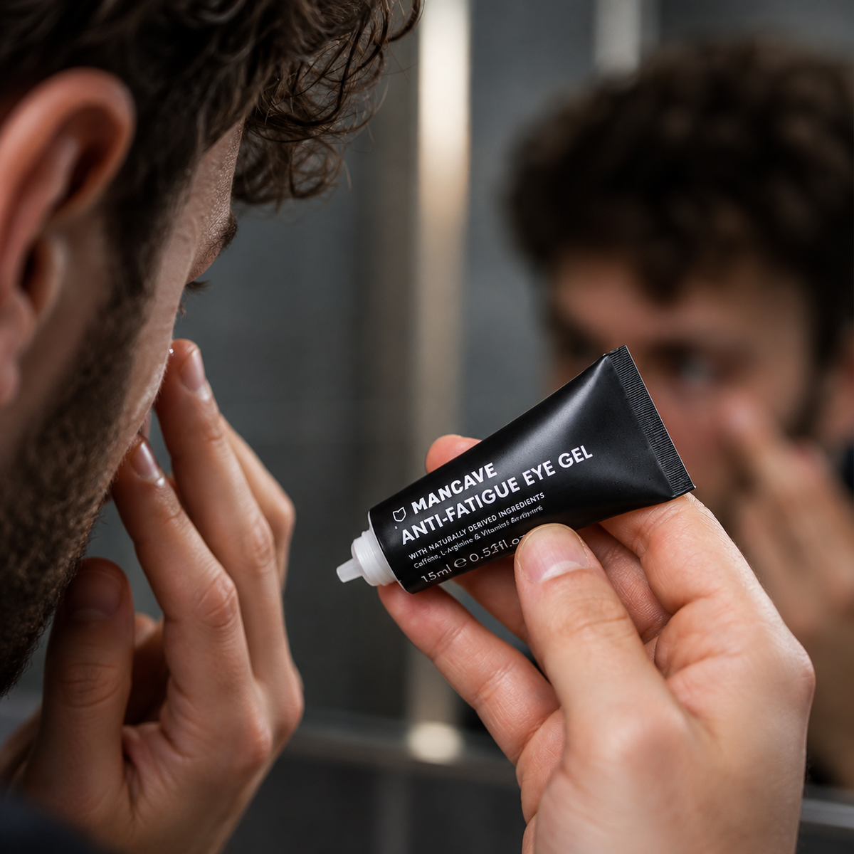 Mann påfører ManCave Anti-Fatigue Eye Gel under øyet foran speilet