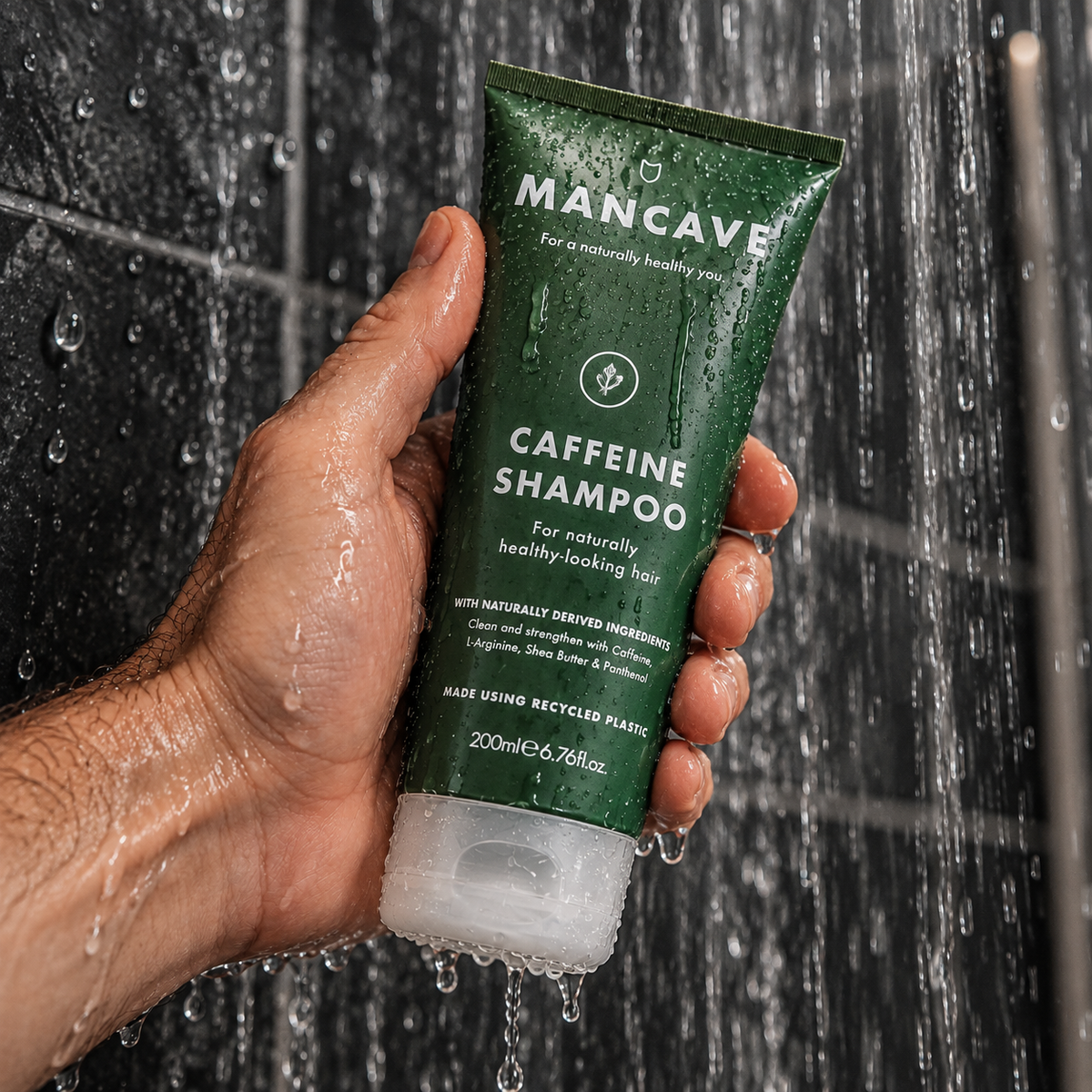 ManCave Caffeine Shampoo holdes i hånden under rennende vann i dusjen